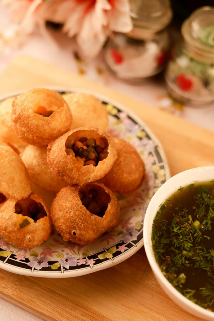 Golden crispy pani puri filled with spices, a popular Indian street food on a plate.
