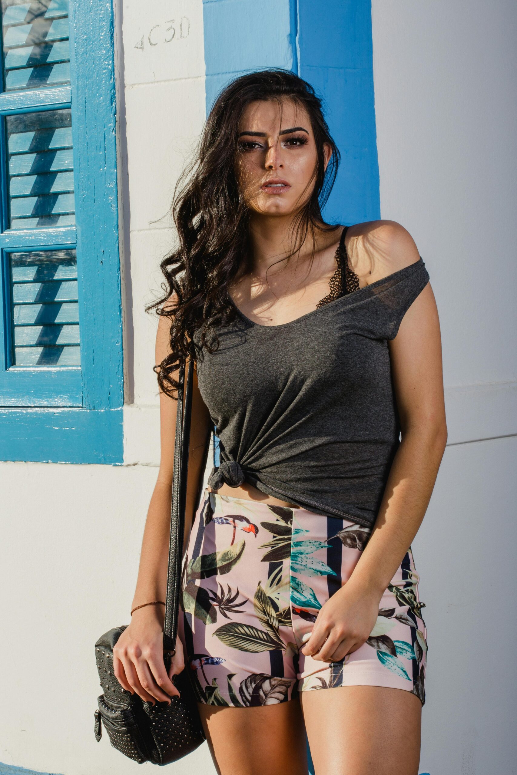 Testimonial Stylish woman posing outdoors in a casual summer outfit with vibrant colors.