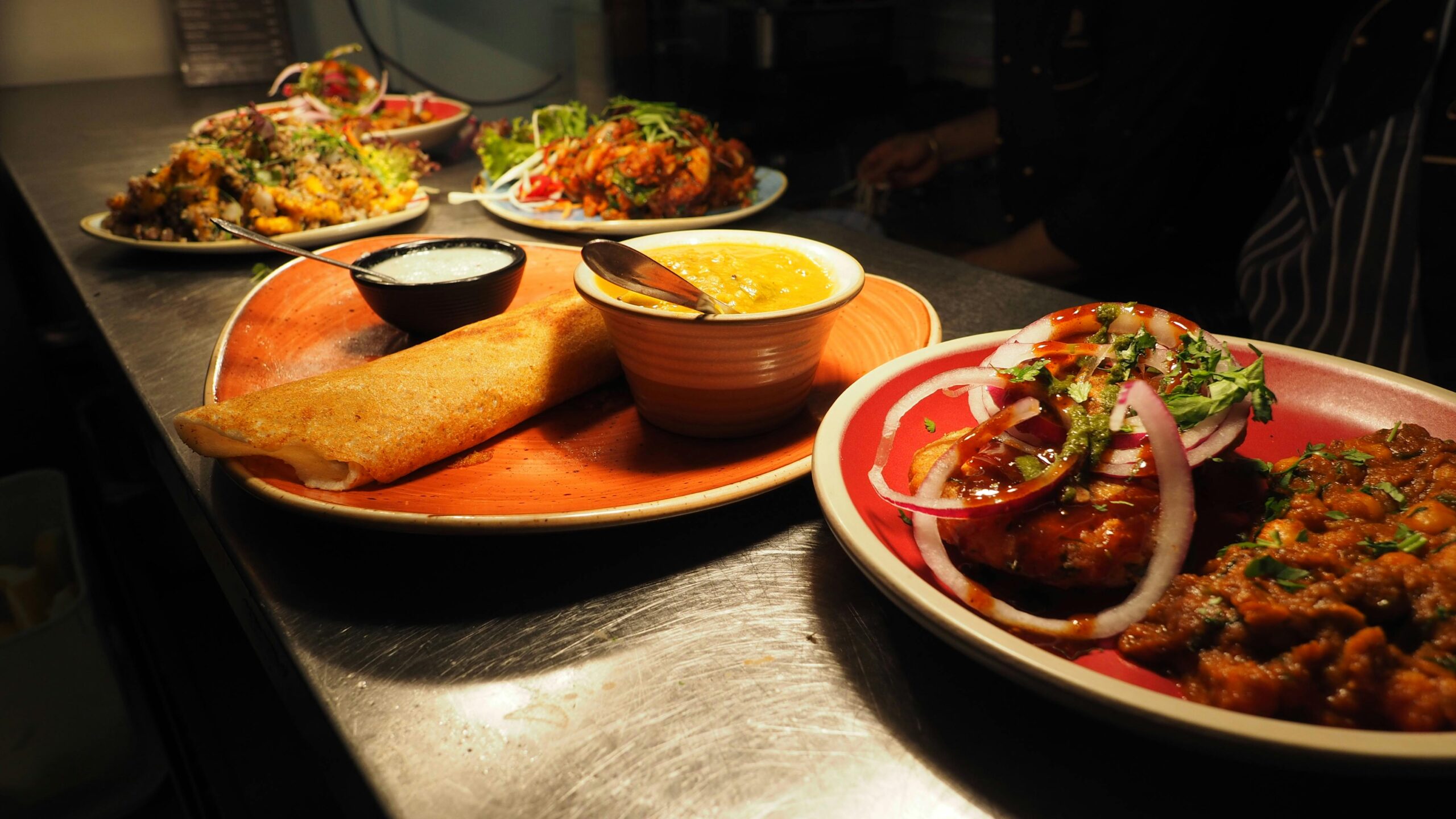 Home A tantalizing array of Indian dishes including dosa, curry, and chutney served on vibrant plates.