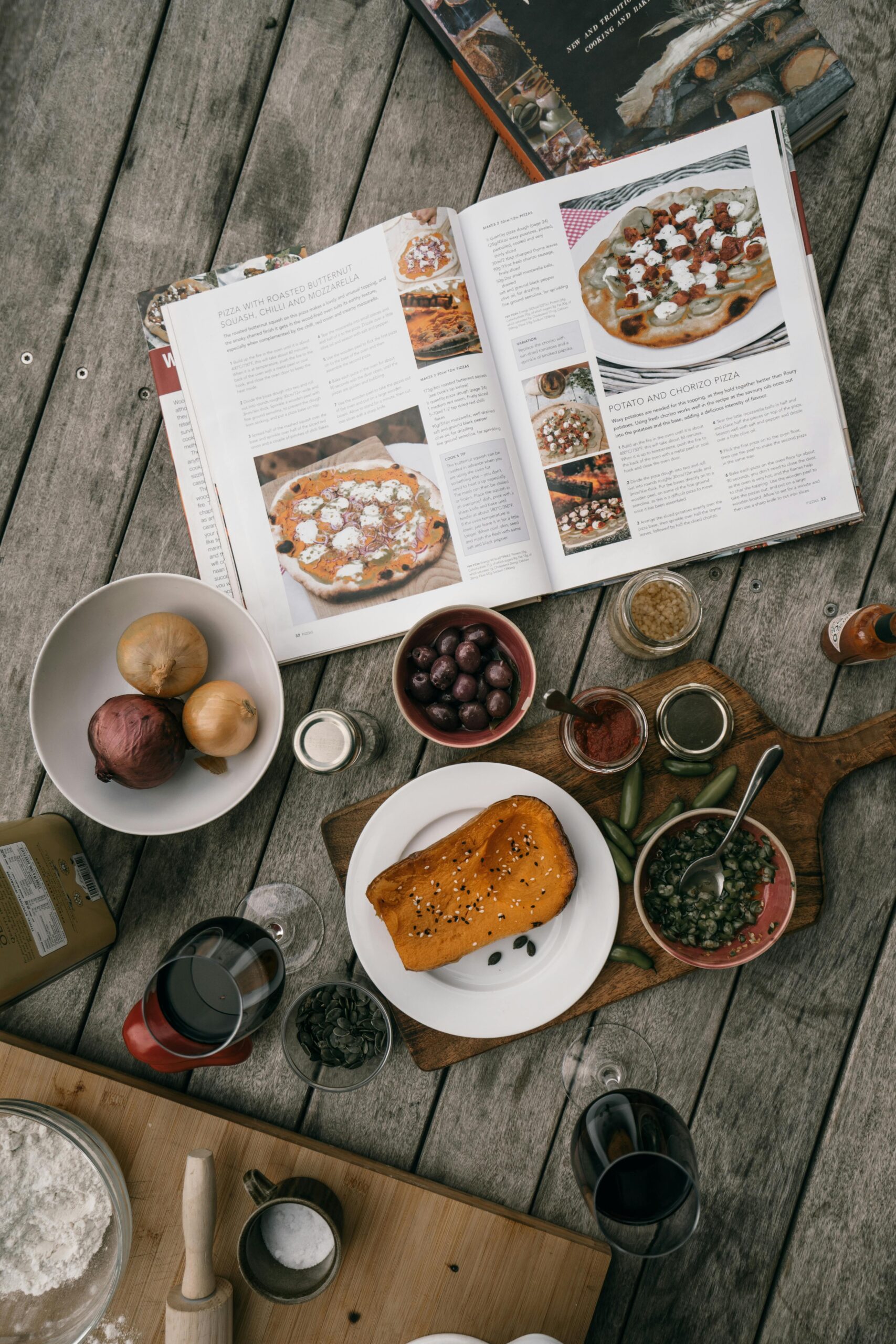 Home Flat lay showing a variety of cooking ingredients and an open cookbook on a rustic wooden table.